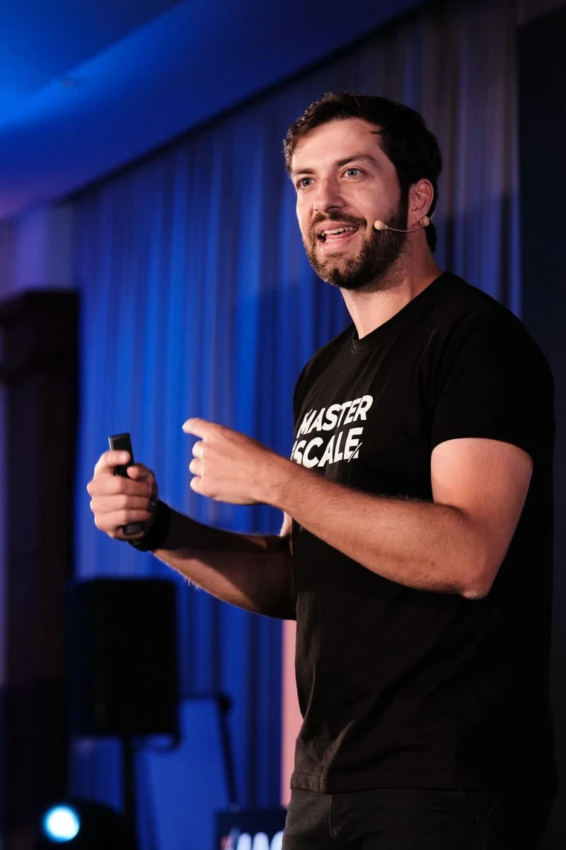 Luciano Larrossa a falar num palco, com microfone